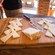 A wooden cutting board with a knife and slices of hard cheese